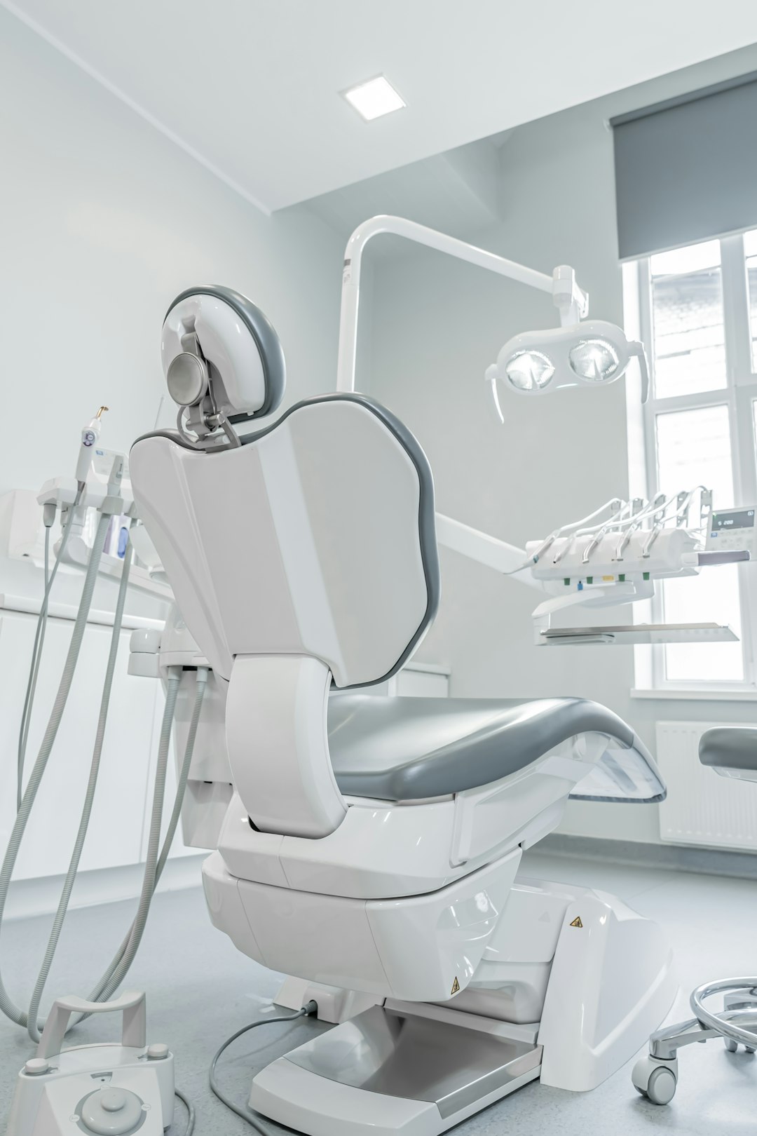 a-white-dental-chair-in-a-room-with-a-window-44jaetsvx2i