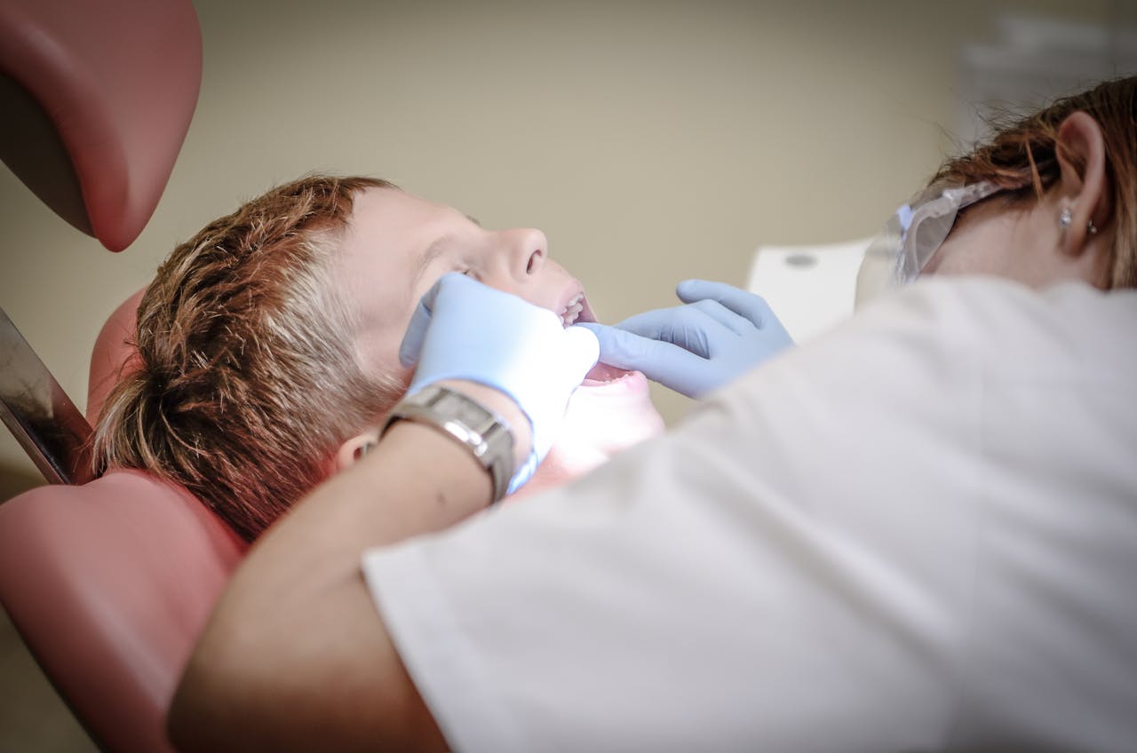 home-services-02 A young boy receiving a dental examination by a professional dentist in a clinic setting.